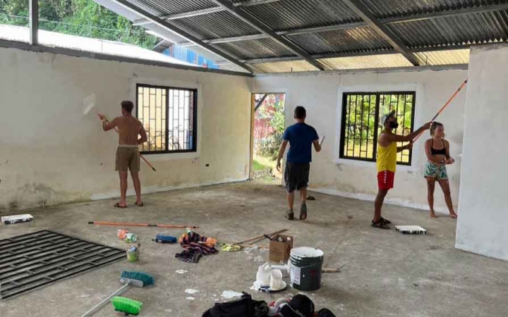 a group of gap year students paint during a service project on an outward bound expedition 